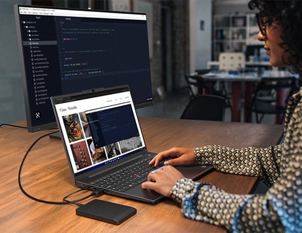 Person at a table, looking at images on a Lenovo ThinkPad E16 (16